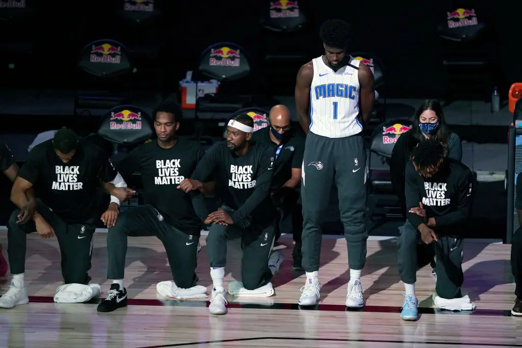 LAKE BUENA VISTA, FL - JULY 31: Jonathan Isaac #1 of the Orlando Magic stands as others kneel before the start of a game between the Brooklyn Nets and the Orlando Magic on July 31, 2020 at The HP Field House at ESPN Wide World Of Sports Complex in Lake Buena Vista, Florida